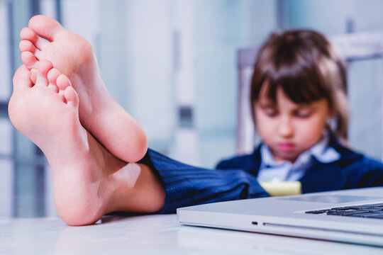 Happy child business girl working and resting at the same time. Selective focus on bare feet.
