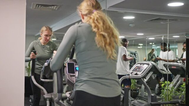 A woman with a sporty figure, in leggings, trains on an orbitrack in the gym