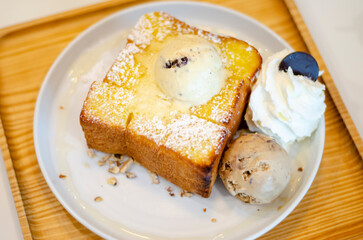 Honey Toast Dessert with Chocolate Ice Cream Chips and mocha almonds on a wooden plate