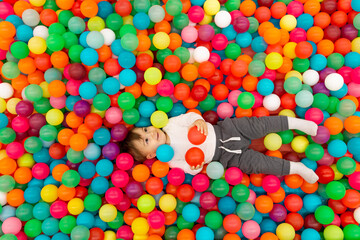 Fototapeta na wymiar Baby playing in a pool with balls, in a children's center, colorful balls, a dry pool.