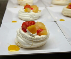 Meringue Pavlova with fruits on a white plate.