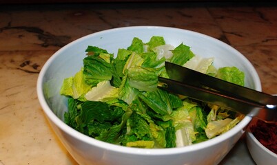 Salad in a bowl with knife and fork on the table.