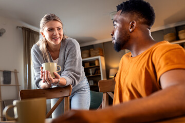 Smiling young mixed couple talking at home in living room.