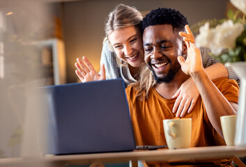 Smiling young mixed couple using a laptop for video call at home.