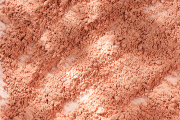 Loose powder for makeup in a natural beige color. Powder texture, cosmetic peach background with copy space.