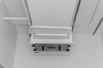 This image shows a large industrial air ventilation unit mounted on a white wall, with venting...