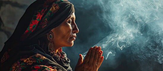 Mexican Latin woman with traditional clothes doing cleansing and spiritual meditations shaman with black shawl long hair pensive and concentrated among incense smoke together praying - obrazy, fototapety, plakaty