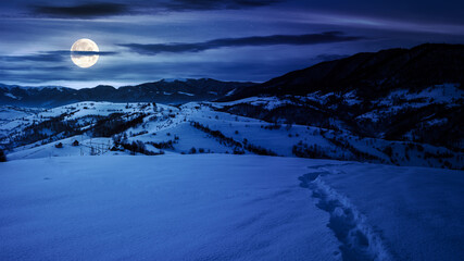 mountainous winter landscape at night. scenery with snow covered hills in the distance beneath...