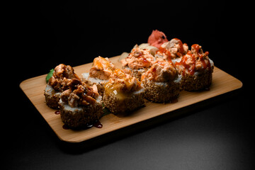 Portion of sushi rolls in sesame with filling and four different sauces