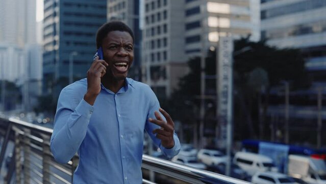 Angry African American Guy Businessman Feeling Furious and Talking on the Phone Outside, Shouting During Call. Mad Boss Yelling on His Colleagues Through the Mobile. People and Emotions Concept