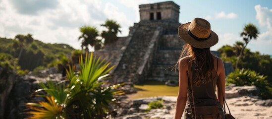 Woman tourist enjoying the view Pre Columbian Mayan walled city of Tulum Quintana Roo Mexico North America Tulum Mexico El Castillo castle the Mayan city of Tulum main temple. Copy space image - obrazy, fototapety, plakaty