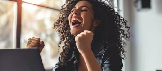 Hispanic business woman celebrating victory success employee with curly hair inside office reading good news using laptop at work inside office holding hand up and happy triumph gesture