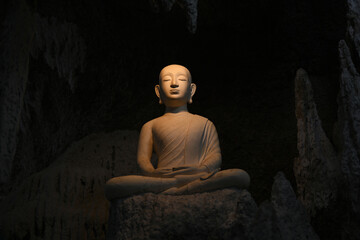 Buddha statue in a cave with light through.