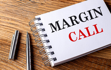 MARGIN CALL text on notebook with pen on wooden background