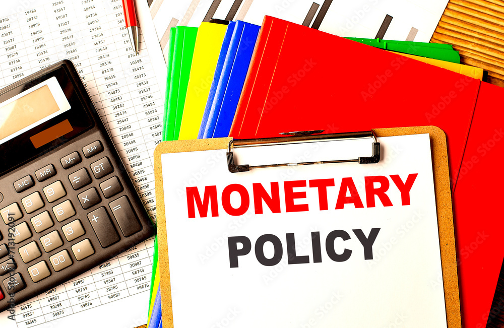 Aufkleber monetary policy text written on paper clipboard with chart and calculator