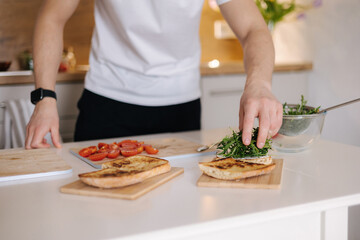 Close-up of man put organic arugula on bruschetta. Vegan food