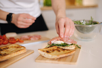 Obraz na płótnie Canvas Man put slice of Italian salami on top of bruschetta. Healthy home made food