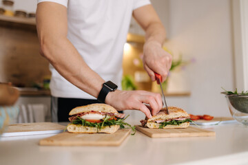 Middle selection of man blogger slice Italian sandwich in the kitchen. Close-up of bruschetta in hands