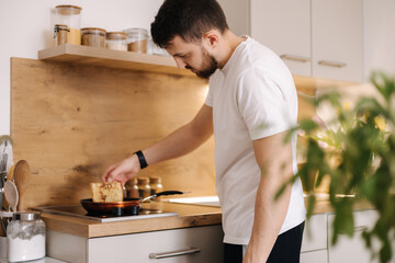 Handsome man preparing food at home. Young male surprise his beloved woman and making breakfast on kitchen