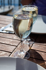 Drinking of white wine at farm cafe in oyster-farming village, with view on boats and water of Arcachon bay, Cap Ferret peninsula, Bordeaux, France
