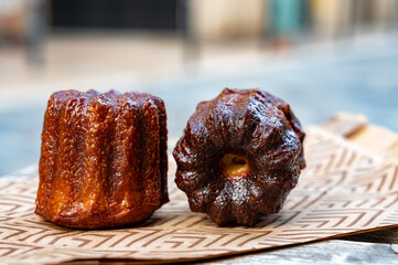 Canele, French pastry flavored with rum and vanilla, soft and tender custard center and  dark, caramelized crust specialty of Bordeaux region, France, streets of Bordeaux on background