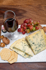 Red porto and cheese pairing, blue matured stilton English cheese served as dessert with walnuts and glass ruby porto wine