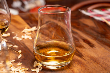 Tasting of different Scotch whiskies strong alcoholic drinks, drum of whiskey and colorful Scotch tartan on background close up
