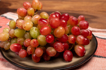 Sweet washed ripe pink grapes berries on board ready to eat