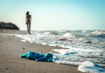 swimsuit in the sand on the beach near the sea surf on the background of a naked female figure and...