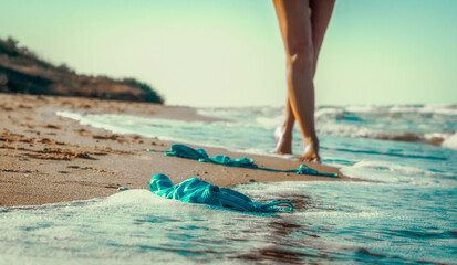 swimsuit in the sand on the beach near the sea surf on the background of a naked female figure and...