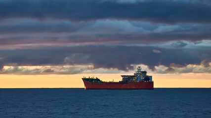 Beautiful  ocean sunset, with colourful blue and golden sky, blue calm ocean and silhouette of ship on the horizon. © Igor Hotinsky