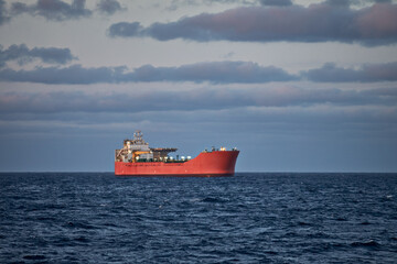 Picture of vessel in the blue sea on a sunny day with cloudy grey and blue sky.