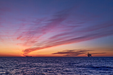 Beautiful sunrise in the sea with colourful pink, yellow, orange and purple sky, blue ocean and...