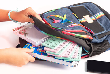 School supplies, teenager's hands putting school supplies into backpack, white background,...