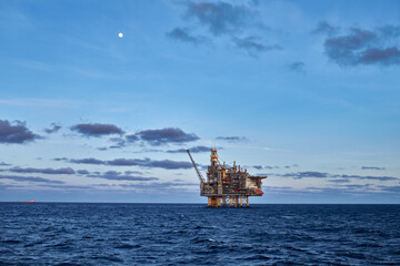 Sunny summer day in the sea, with blue sky and clouds, and silhouette jack up drilling rig on the...