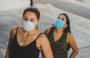 mujeres jovenes usando mascarillas en  tiempos de pandemia al aire libre 