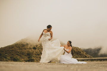 Fototapeta na wymiar pareja gay de mujeres recién casadas paseando al aire libre por las montañas con sus vestidos de novia
