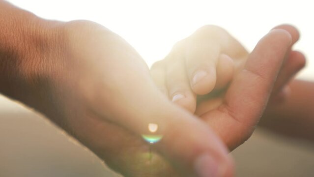 Hand in hand close up.father holds child's hand.baby's dream.hands baby and dad together at sunset outdoors.clasped hands as sign support.helping hand.happy child.family support.happy family concept