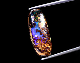 natural rainbow boulder opal gem on the background