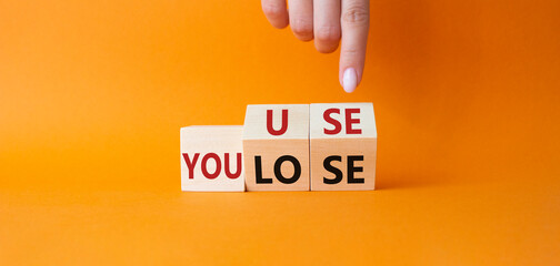 You use or lose symbol. Businessman hand points at cubes with words You lose or You use. Beautiful orange background. Business and You use or lose concept. Copy space