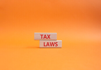 Tax Laws symbol. Concept word Tax Laws on wooden blocks. Beautiful orange background. Business and...