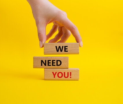 We need you symbol. Concept words We need you on wooden blocks. Beautiful yellow background. Businessman hand. Business and We need you concept. Copy space.