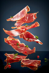 Slices of cured ham jamon Serrano Proscuitto, levitation floatinf food, black background..
