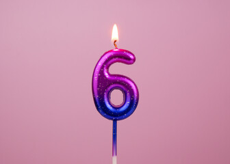 Pink and blue birthday candle burning on pink background. Number 6.