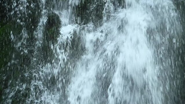 Water showering the ground in front of a waterfall (slow motion)