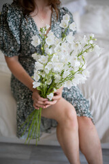 Bouquet of white flowers in hands. Wildflowers on the background.