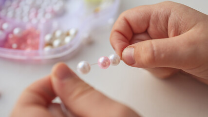 Child makes decoration from beads, creative concept