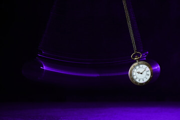 Hypnosis session. Vintage pocket watch with chain swinging over surface on dark background among...