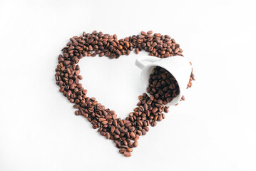 A heart made of coffee beans and a coffee cup is laid out on a white background.