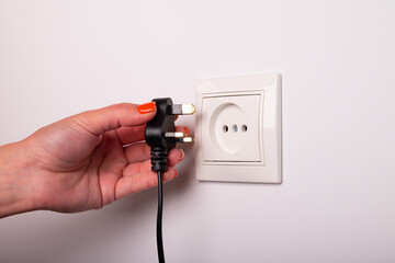 Different standards for electrical outlets. Unsuitable connector and plug in the hand of a person....
